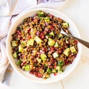 Serving bowl of lentil salad with a spoon in it.